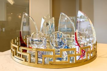A glass trophy with a gold base and a red ribbon is displayed on a table.